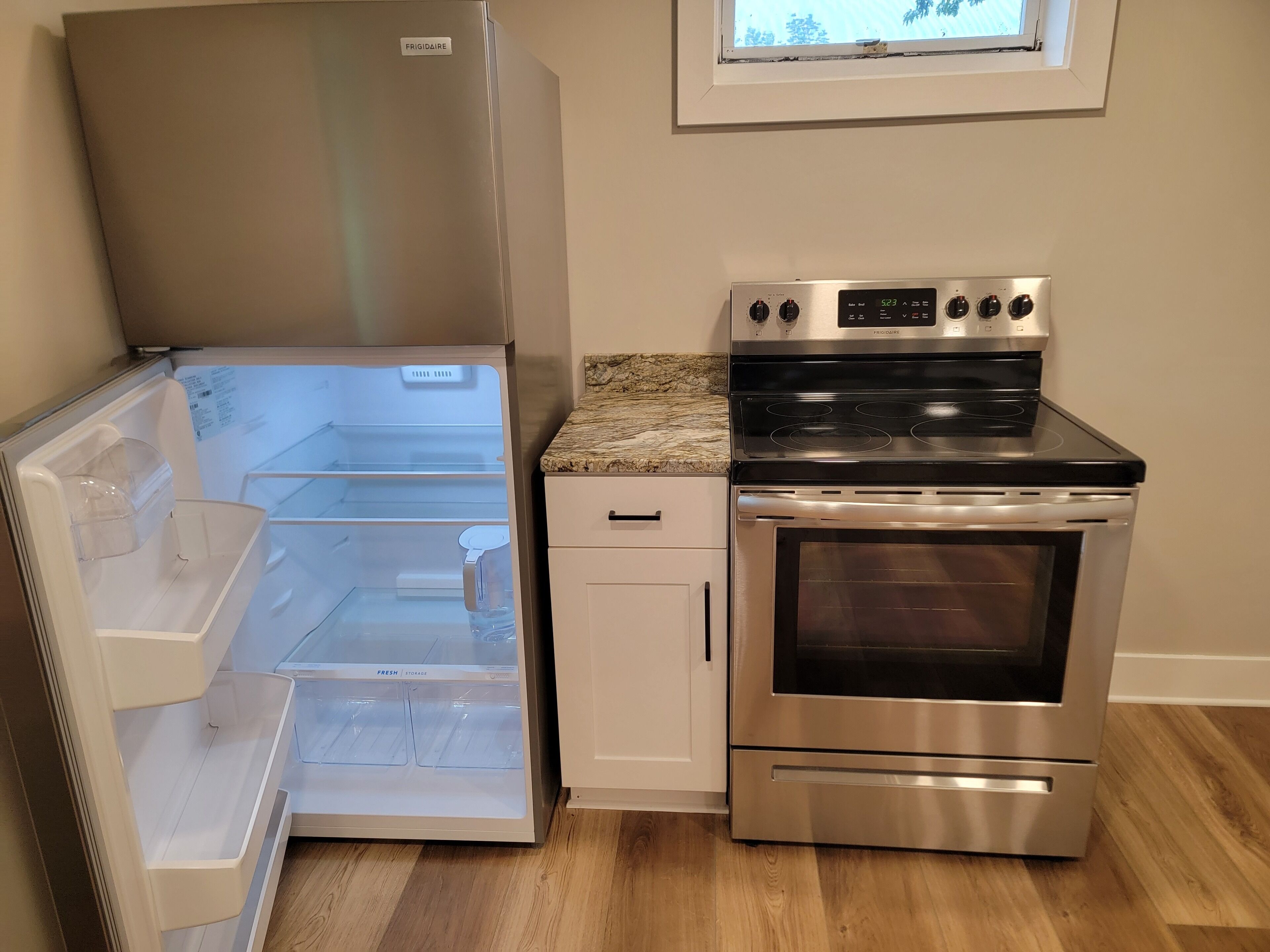 Una cocina con un refrigerador de acero inoxidable, horno empotrado y microondas.