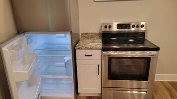 Una cocina con un refrigerador de acero inoxidable, horno empotrado y microondas.