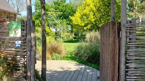 A wooden pathway leading to a rustic building with a sign indicating it's a Gîte in Côtes d'Armor, France. - De Rulinen - Orchard side (SAINT CLET)