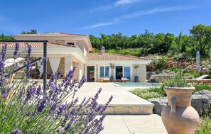 Une maison avec une piscine, un espace salon extérieur et un jardin agrémenté de lavande.