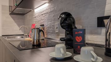 Cozinha moderna com cafeteira, duas chávenas e uma caixa de cápsulas Morettino Mediterrânico.