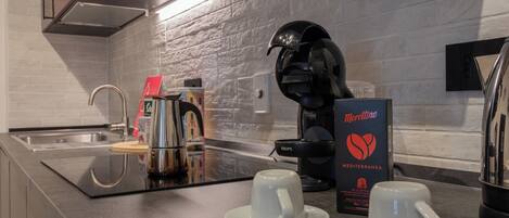 A modern kitchen with a coffee maker, two cups, and a box of Morettino Mediterranean capsules.