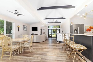 Una cocina amplia con electrodomésticos modernos, un comedor con sillas de madera y vistas al exterior.