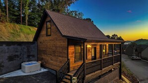 A wooden cabin with a porch, a hot tub, and a sign indicating it's a time rental resort. - New Construction, Hot Tub, Mountain View, 4 Miles to Dollywood, Pac Man (Sevierville)