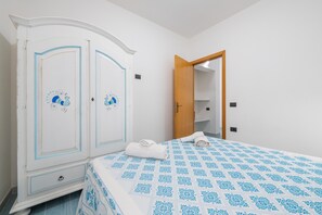 Un dormitorio con cama, armario y puerta abierta que da a un baño.