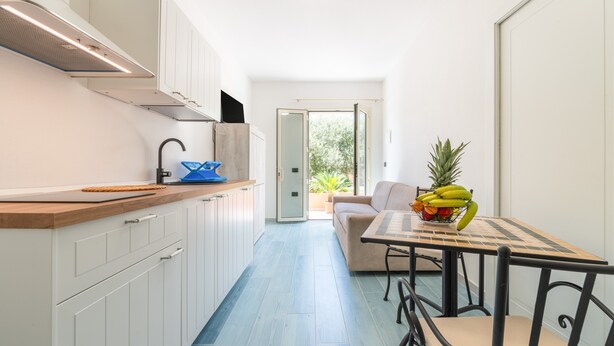 Una cocina moderna con armarios blancos, encimera de madera y comedor con mesa y sillas.