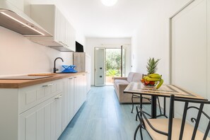 A modern kitchen with white cabinets, a wooden countertop, and a dining area with a table and chairs.