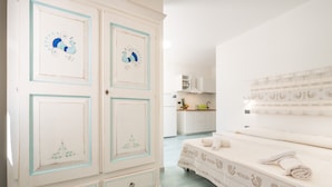 Une chambre avec un lit, une armoire et un coin cuisine.