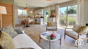 A spacious living area with a sofa, chairs, a dining table, and a kitchen in the background.