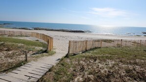 A wooden pathway leading to a sandy beach with a wooden fence.