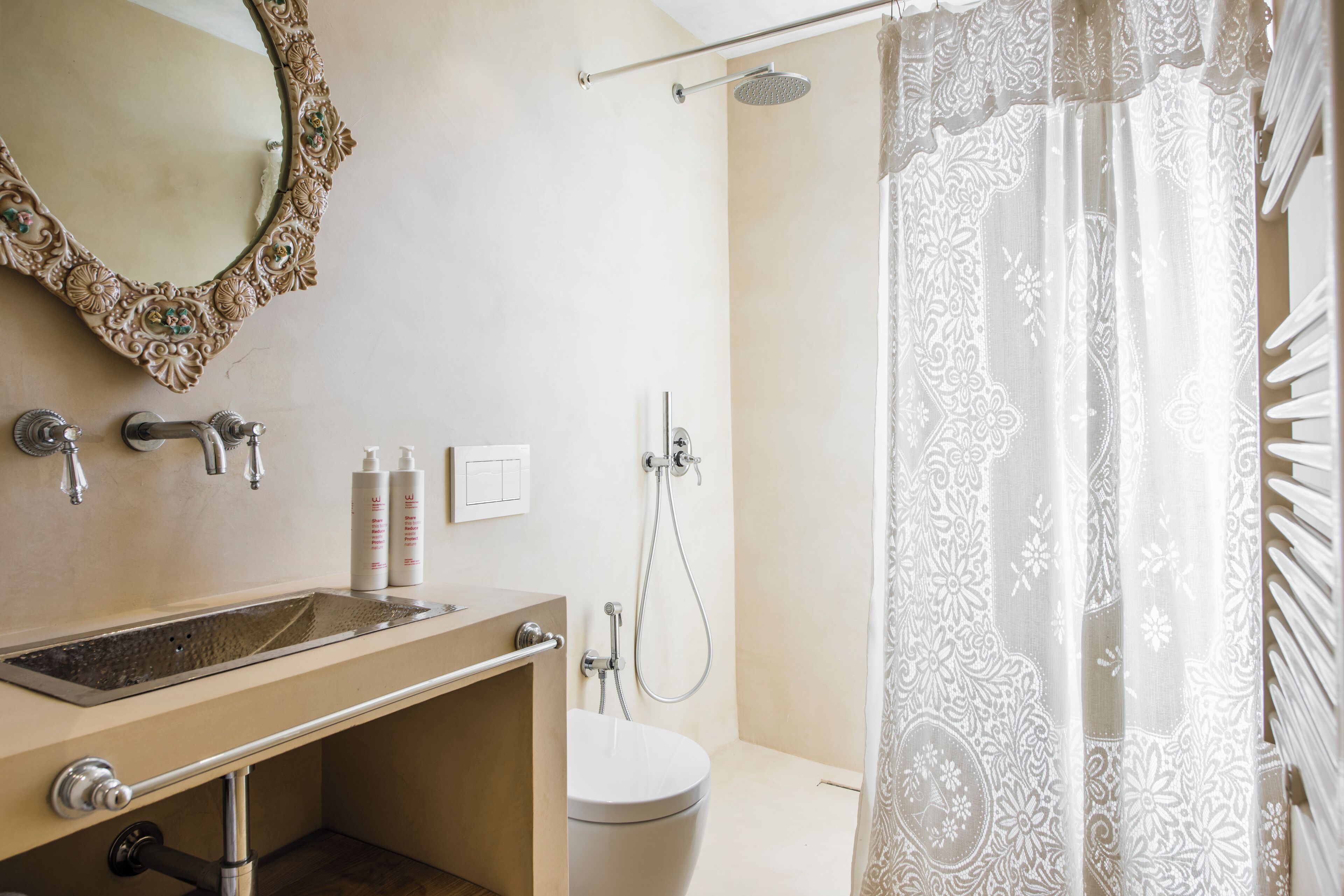 Un baño con lavamanos, espejo, inodoro, ducha y cortina de ducha estampada.