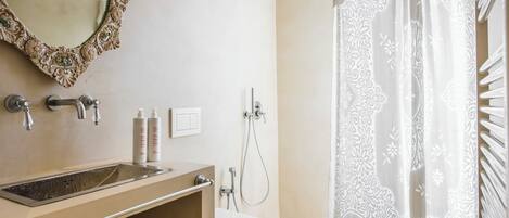 Un baño con lavamanos, espejo, inodoro, ducha y cortina de ducha estampada.