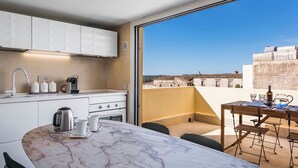 A modern kitchen with white cabinets, a marble countertop, and a view of the city through large windows. - Casa Novella con Terrazza by Wonderful Italy (Noto)