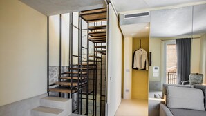 A modern interior with a spiral staircase, a sofa, and a hanging coat rack. - Casa Novella con Terrazza by Wonderful Italy (Noto)