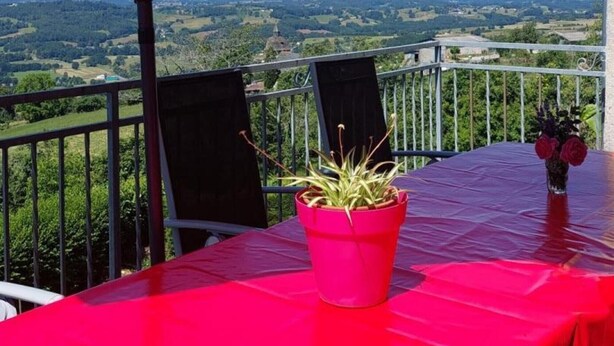 A balcony with a table, chairs, a potted plant, and a tablecloth. - Holiday Home 'Gîte La Chartrouille' with Private Terrace, Private Garden and Wi-Fi (Allassac)