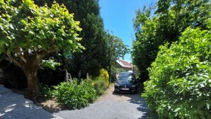A paved driveway leading to a parked car, surrounded by lush greenery and trees. - Holiday Home 'Gîte La Chartrouille' with Private Terrace, Private Garden and Wi-Fi (Allassac)