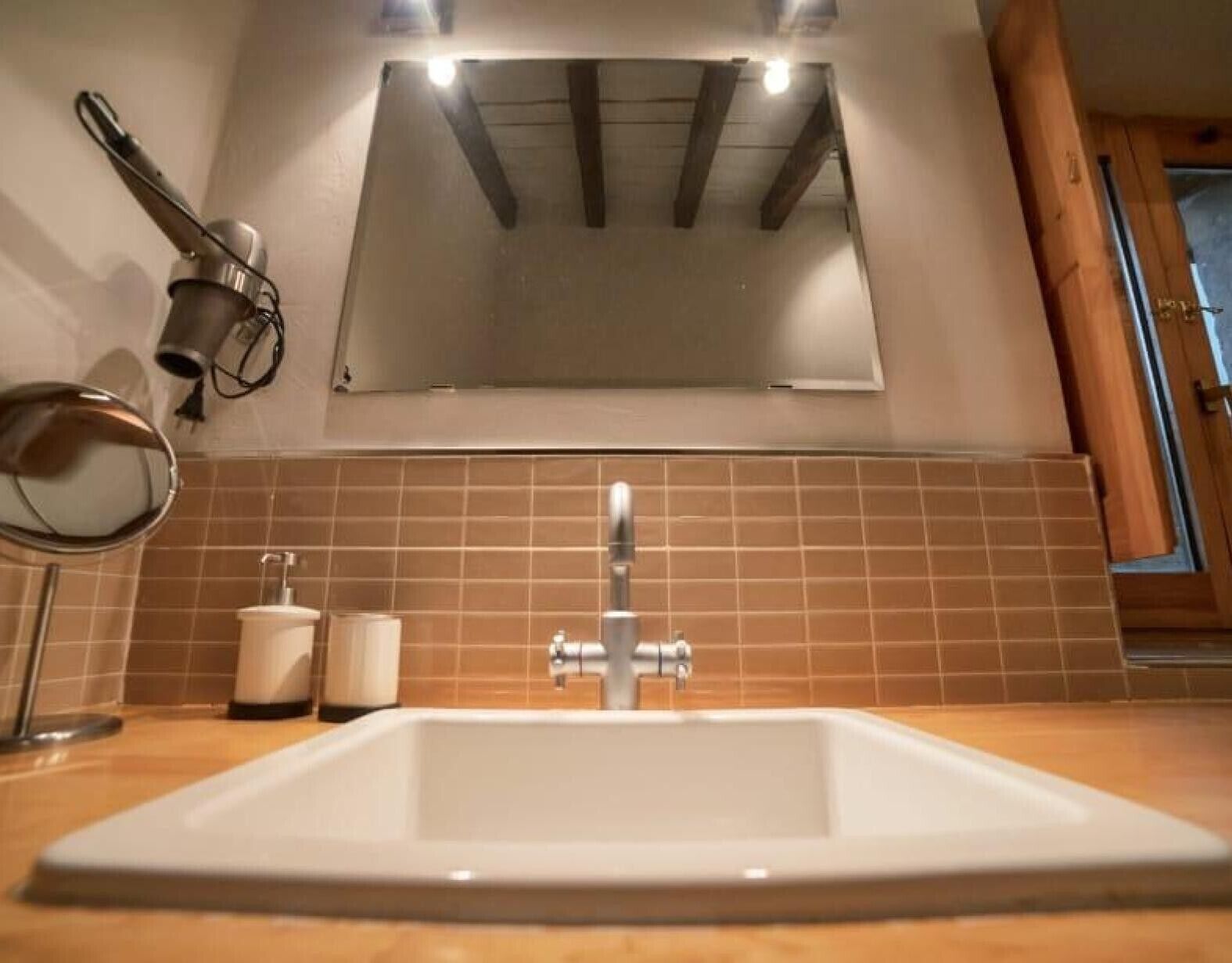 Une salle de bain avec un lavabo blanc, un miroir et un distributeur de serviettes.