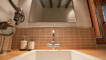 Une salle de bain avec un lavabo blanc, un miroir et un distributeur de serviettes.