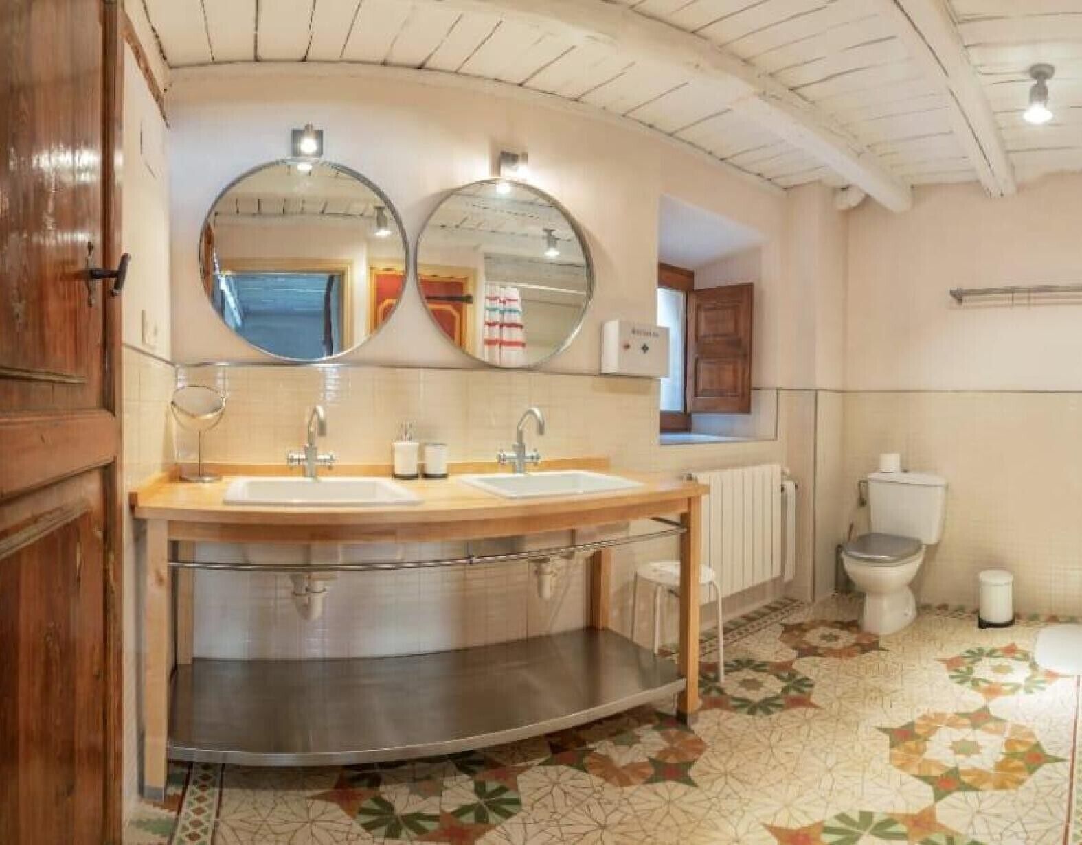 Un baño con dos lavamanos, un espejo, un inodoro y un radiador.