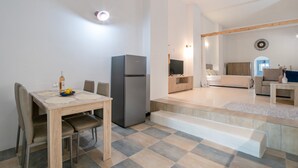Une pièce moderne et bien éclairée, comprenant une table à manger, des chaises, un réfrigérateur, un canapé et un téléviseur.
