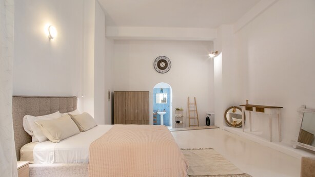Une chambre à coucher avec un lit, une commode, un miroir et une horloge au mur.