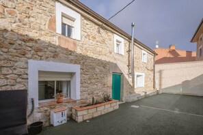 A stone building with a window, a door, and a small outdoor area with a bench and potted plants. - Casa La Molina – Spacious Countryside Home with Mountain Views near Burgos (Burgos)