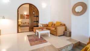 Uma sala de estar moderna com um sofá, uma mesa de centro, um tapete, uma porta de madeira e um espelho fixado na parede.