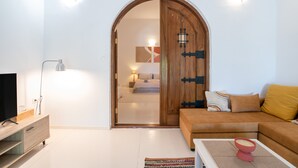 Uma sala de estar moderna com porta de madeira, um sofá, uma mesa de centro e uma TV.