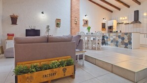 A cozy living room with a sofa, a wooden planter with greenery, a dining area with a table and chairs, and a kitchen with a tiled backsplash. - Country House Near Arribes del Duero - Sardón de los Frailes, Salamanca (Sardón de los frailes)