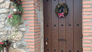 A wooden door with a wreath, a bell, and greenery on a stone and brick wall. - Country House Near Arribes del Duero - Sardón de los Frailes, Salamanca (Sardón de los frailes)