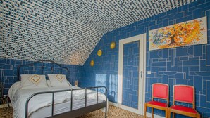 A bedroom with a patterned blue and white ceiling, a bed with white bedding, two red chairs, and a door with a geometric pattern. - Chez Alice - VILLENAUXE LA GRANDE (VILLENAUXE LA GRANDE)