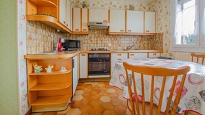 A compact kitchen with wooden cabinets, a microwave, an oven, and a dining table with chairs. - Chez Alice - VILLENAUXE LA GRANDE (VILLENAUXE LA GRANDE)
