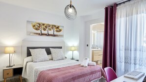 Ein Hotelzimmer mit Bett, Nachttischlampen, einem Schreibtisch mit Laptop, einem Gemälde an der Wand und einem Fenster mit Vorhängen.