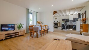 A modern living room with a TV, dining area, and kitchen.