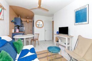 Een moderne woonkamer met een bank, een televisie, een eettafel en een keukenhoek.