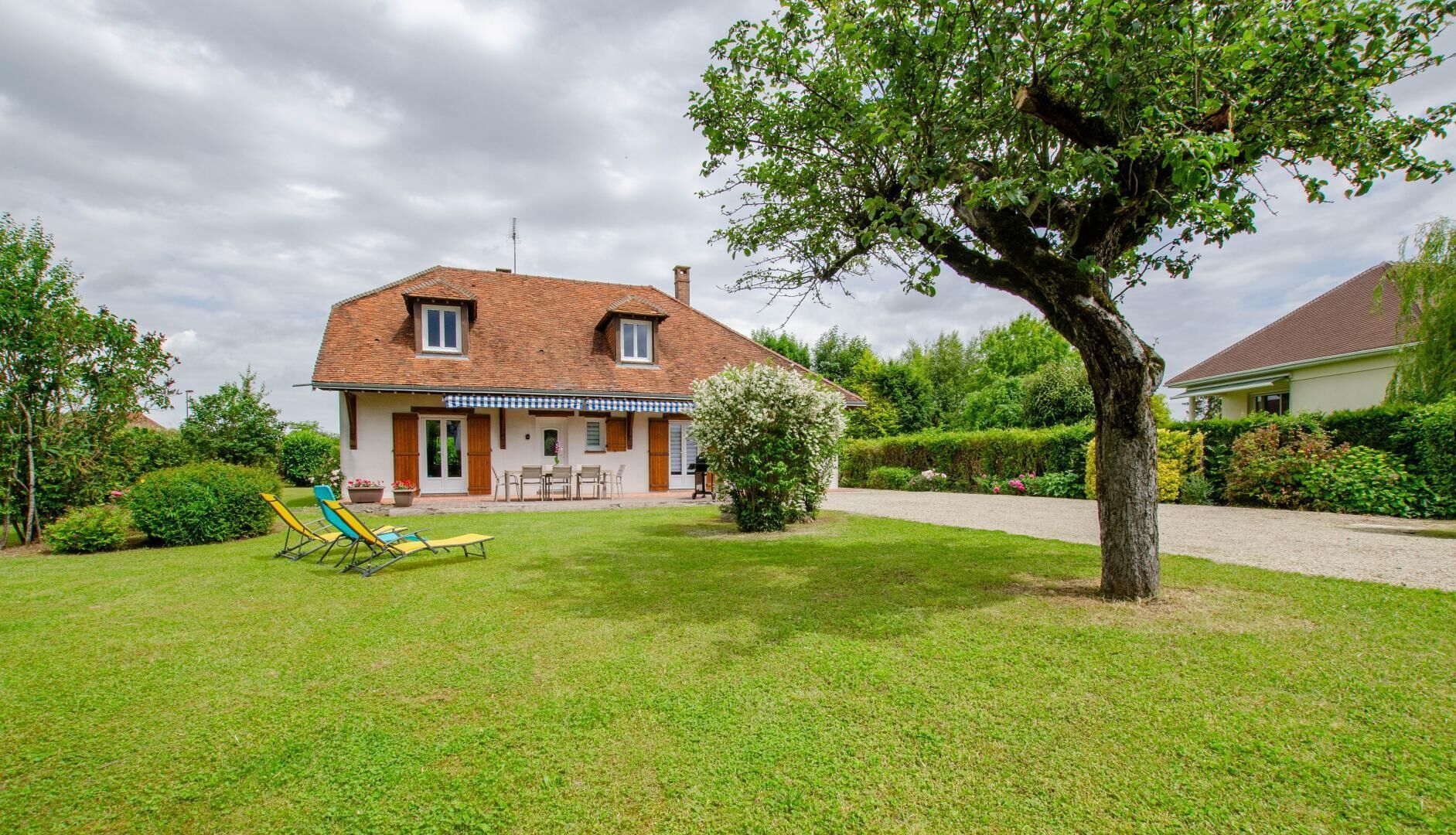 A two-story house with a tiled roof, a front porch, and a well-maintained lawn.