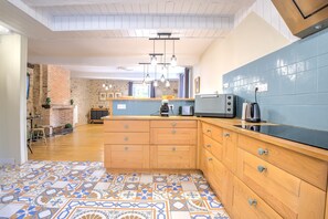 A kitchen with wooden cabinets, a blue backsplash, and patterned floor tiles.