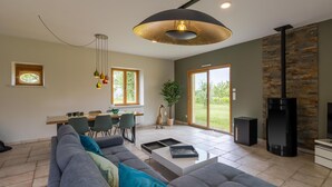 Una sala de estar moderna con sofá, mesa de comedor, sillas, una mesita de centro, chimenea y un ventanal grande.