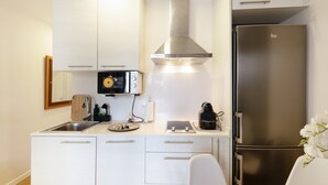 A modern kitchen with white cabinets, a stainless steel range hood, a refrigerator, and a coffee maker. - Apartment 'Bonito Apartamento En Gava Mar' with Private Terrace, Wi-Fi and Air Conditioning (Gavà)