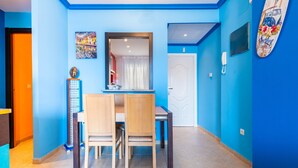 A dining area with a table and chairs, a mirror, a decorative item, and a surfboard on the wall.