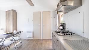 Une cuisine moderne équipée d’une cuisinière à gaz, de meubles en bois et d’un coin repas avec une table et des chaises.