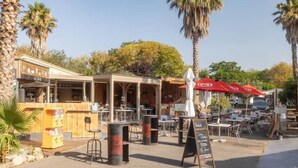 Un café en plein air avec des tables et des chaises, un bar et une enseigne.