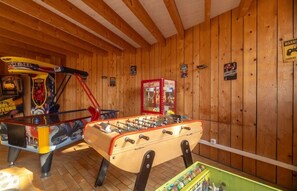 Ein Zimmer mit Holzboden, einem Tischkicker und Spielautomaten.