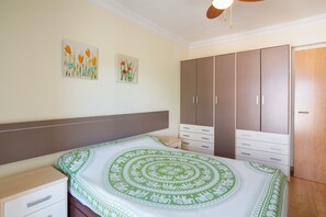Une chambre à coucher comprenant un lit, une armoire et deux tableaux accrochés au mur.