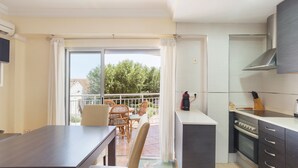 A modern kitchen with a dining area, a balcony with a table and chairs, and a large window. - Apartment 'La Paz De Xinxilla' with Sea Views, Wi-Fi and Air Conditioning (Dénia)