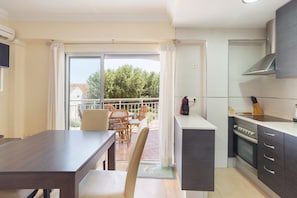 Une cuisine moderne avec un coin repas, un balcon doté d’une table et de chaises, et une grande fenêtre.