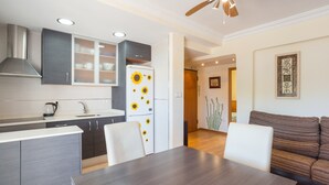 A modern kitchen with a white refrigerator, dark cabinets, and a dining area with a wooden table and white chairs. - Apartment 'La Paz De Xinxilla' with Sea Views, Wi-Fi and Air Conditioning (Dénia)
