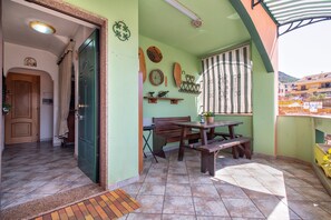 A room with a green wall, a wooden door, a bench, a table, and a window with a striped curtain.