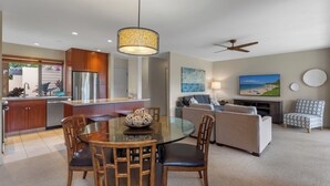 A modern kitchen with a dining area, a sofa, and a ceiling fan.
