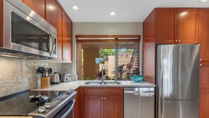 A modern kitchen with stainless steel appliances, wooden cabinets, and a granite countertop.